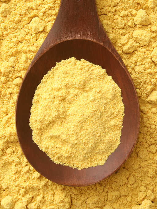 Top view of wooden spoon with mustard powder on it