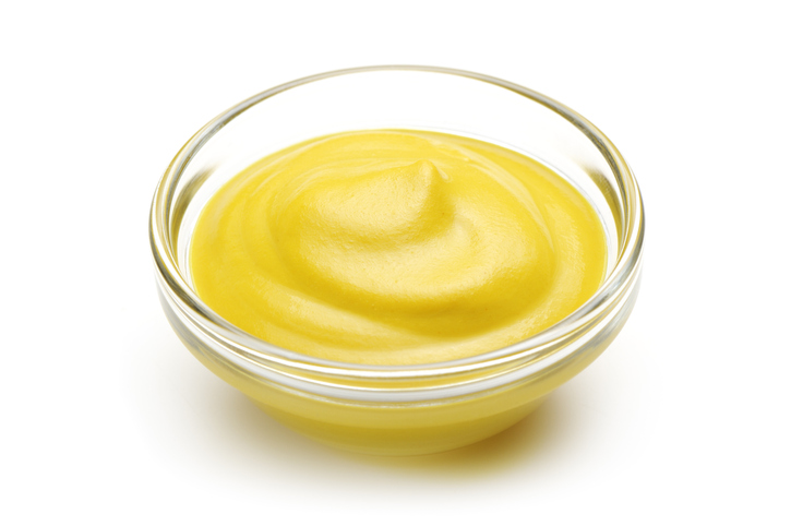 "Yellow mustard in a small side bowl, isolated on white"
