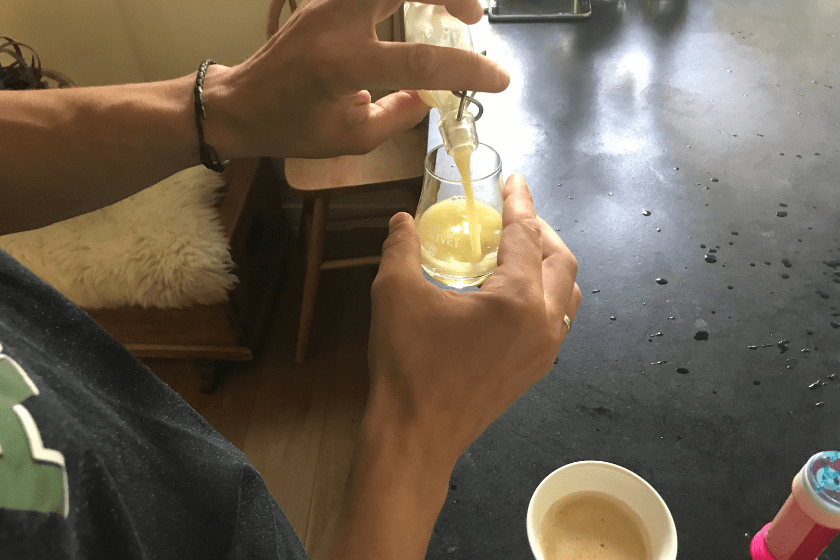 man pouring ginger shot over black counter