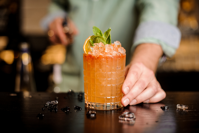 man places homemade triple sec cocktail on countertop