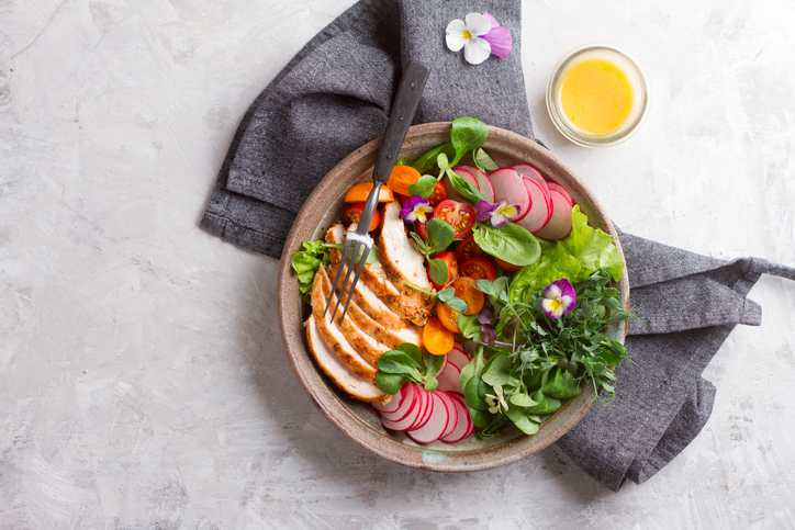 Spring salad with vegetables, chicken breast and edible floweSpring salad with vegetables, chicken breast and edible flowe