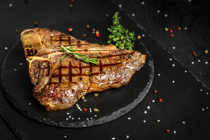 Grilled BBQ T-Bone Steak or porterhouse steak with Fresh Rosemary. American cuisine. Restaurant menu, dieting, cookbook recipe. The concept of pral cooking meat