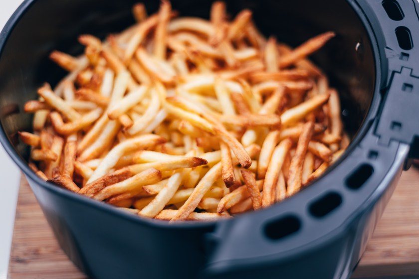 Air fryer with french fries on the worktop