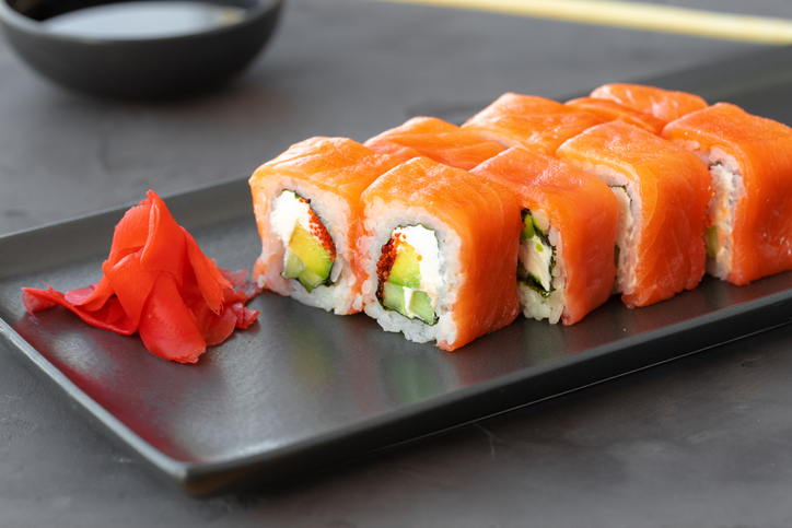 Philadelphia sushi roll served on black ceramic plate close up