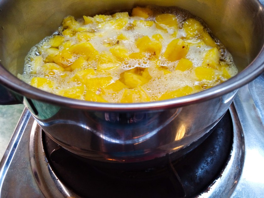Cooking a pot of pineapple cubes.