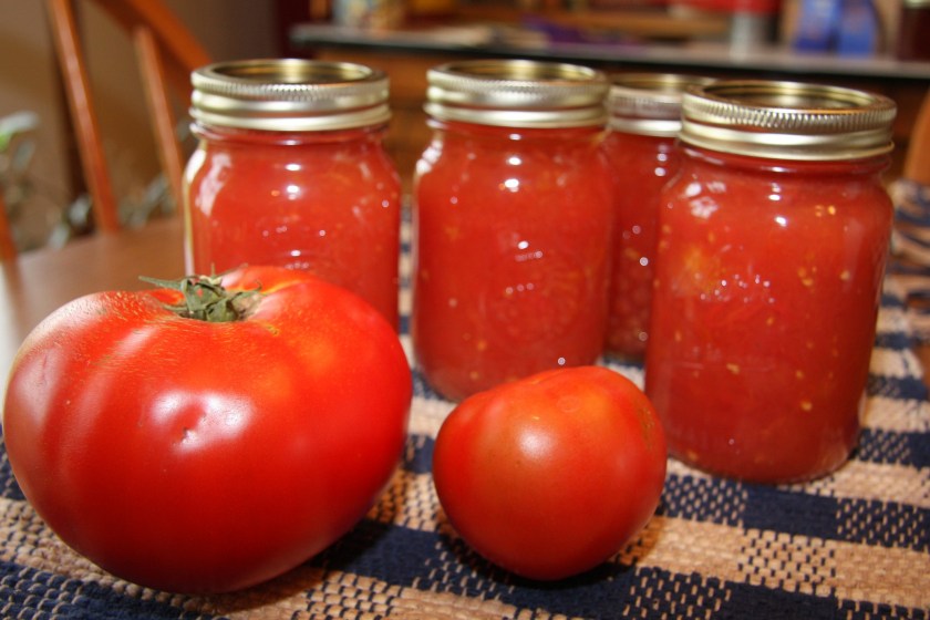 cans of tomatoes and fresh tomatoes on a table