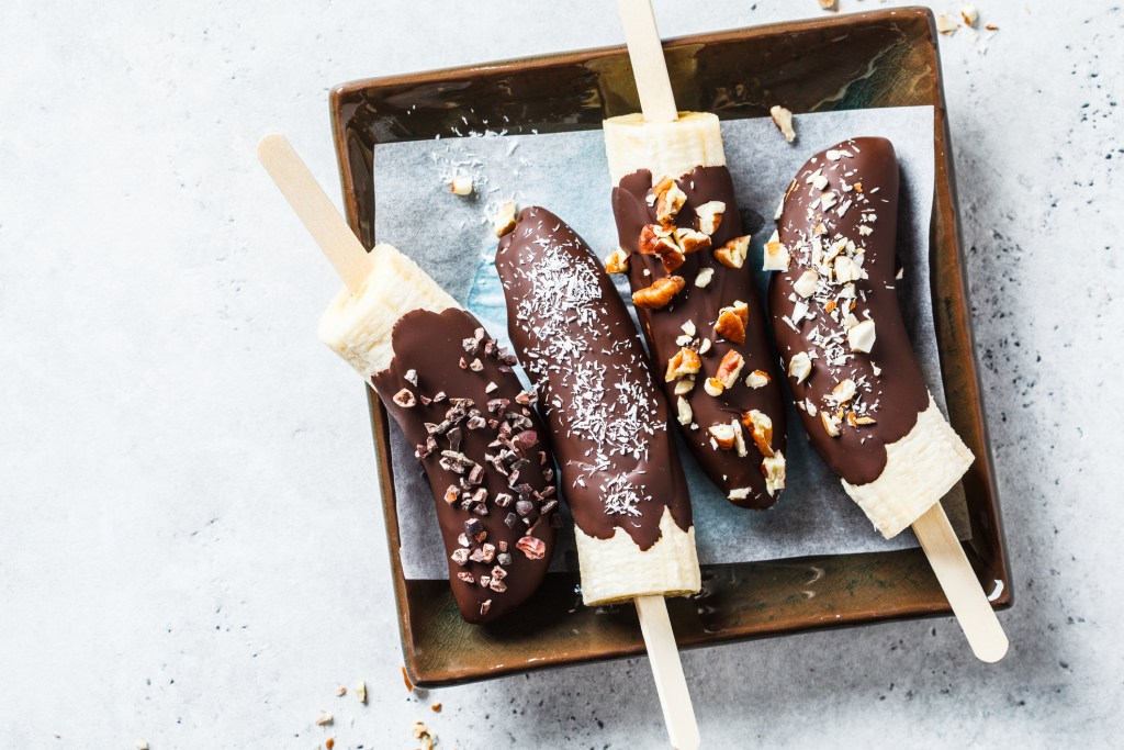 Vegan dessert for kids. Banana in dark chocolate with nuts.